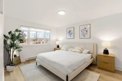 a white bedroom with a bed and a window at The Samson Haven in Laval