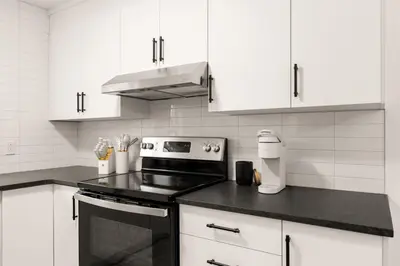 a kitchen with white cabinets and a stove top oven at The Samson Haven in Laval