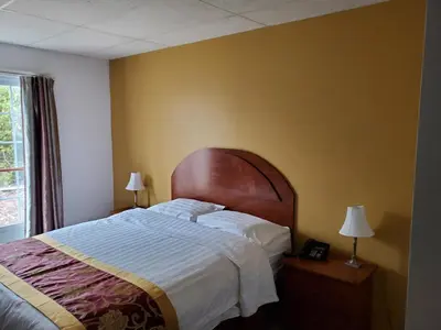 a bedroom with a large bed with a wooden headboard at Motel châteauterrebonne in Terrebonne