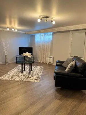 a living room with a black leather couch and a table at Residence Havre d'abraham in Laval