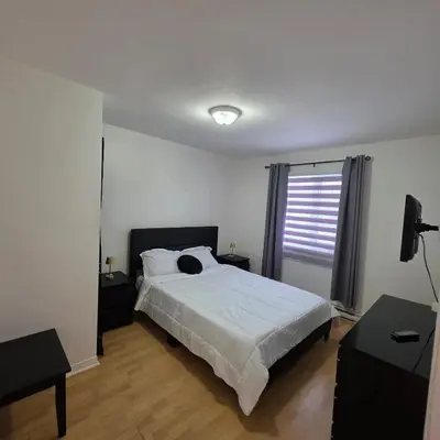 a white bedroom with a bed and a window at Appartement cosy, comme à la maison in Montréal