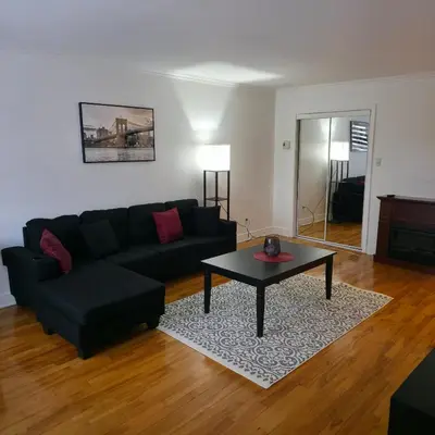 a living room with a black couch and a coffee table at Appartement cosy, comme à la maison in Montréal