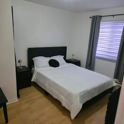 a bedroom with a bed with white sheets and a window at Appartement cosy, comme à la maison in Montréal