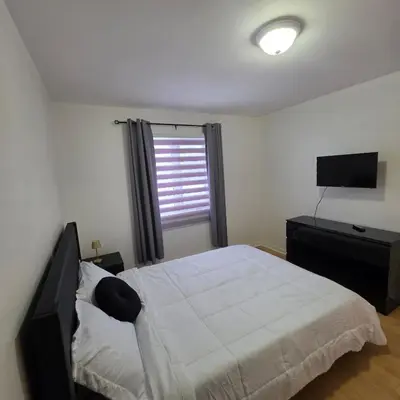 a bedroom with a large bed and a television at Appartement cosy, comme à la maison in Montréal