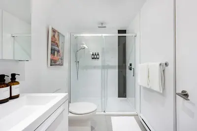 a white bathroom with a shower and a toilet at La Parisienne in Old Montreal -Downtown Montreal - Laundry in Montréal