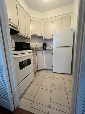 a kitchen with white cabinets and a white refrigerator at Studio in Montreal downtown-Free WIFI-Beside metro station Guy-Concordia in Montréal