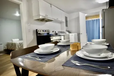 a kitchen with a table with bowls and plates on it at Modern, cozy, near Metro, Place Bell, Free Parking in Laval