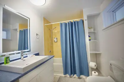 a bathroom with a sink and a blue shower curtain at Modern, cozy, near Metro, Place Bell, Free Parking in Laval