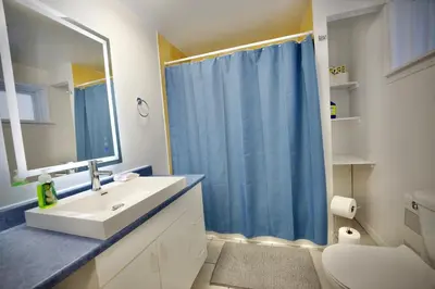 a bathroom with a sink and a blue shower curtain at Modern, cozy, near Metro, Place Bell, Free Parking in Laval