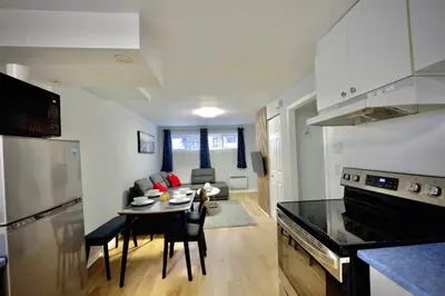a kitchen and living room with a table in a room at Modern, cozy, near Metro, Place Bell, Free Parking in Laval