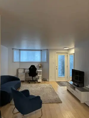 a living room with a blue couch and a television at Cozy fully-furnished appartement in St-Rose Laval in Laval