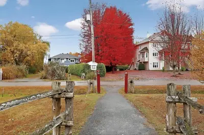 a wooden fence in front of a house with a red tree at Condo ÉVASION in Magog-Orford