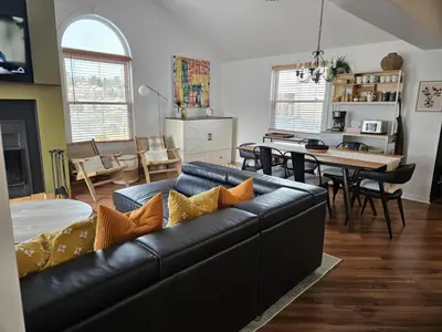 a living room with a black leather couch and a dining room at Condo ÉVASION in Magog-Orford