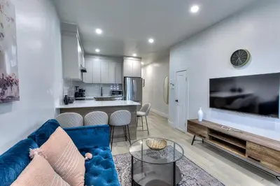 a living room with a blue couch and a kitchen at Montreal's Downtown Glow & Go 2BR Apartment in Montréal