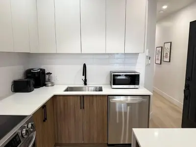 a white kitchen with a sink and a microwave at Montreal's Downtown Glow & Go 2BR Apartment in Montréal