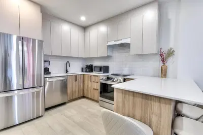 a kitchen with white cabinets and stainless steel appliances at Montreal's Downtown Glow & Go 2BR Apartment in Montréal