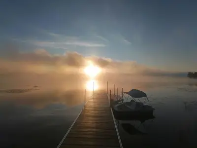a dock with a boat on the water at sunset at Lake & Game Room - Chalet Brothers and Sun in Disraeli