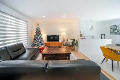 a living room with a black couch and a christmas tree at 4 beds entire house, 15 mins to MTL in Brossard
