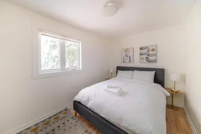 a white bedroom with a bed and a window at 4 beds entire house, 15 mins to MTL in Brossard