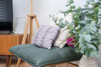 a green chair with pillows on it next to a plant at 4 beds entire house, 15 mins to MTL in Brossard