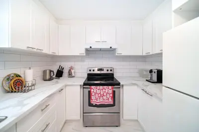 a white kitchen with a stove and white cabinets at 4 beds entire house, 15 mins to MTL in Brossard