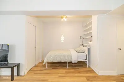 a white bedroom with a bed and a tv at Studio in heart of DT,walk to 2 metros,Concordia in Montréal
