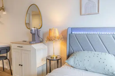 a bedroom with a bed with a blue headboard and a mirror at Studio in heart of DT,walk to 2 metros,Concordia in Montréal
