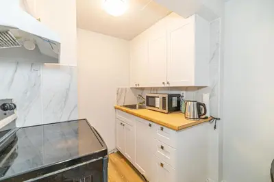 a kitchen with white cabinets and a microwave at Studio in heart of DT,walk to 2 metros,Concordia in Montréal