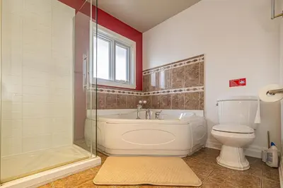 a bathroom with a tub and a toilet and a window at Unique Waterfront House 4 BDRs, Near MTL, Fishing in Laprairie