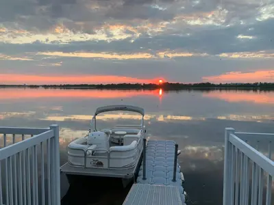 a boat tied up to a dock on a lake at Unique Waterfront House 4 BDRs, Near MTL, Fishing in Laprairie