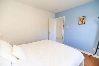 a bedroom with a white bed and a blue wall at Spacious 4BDRS Entire House near DT, Free Parking in Longueuil