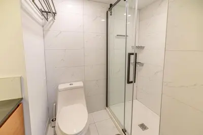 a bathroom with a toilet and a glass shower at Spacious 4BDRS Entire House near DT, Free Parking in Longueuil