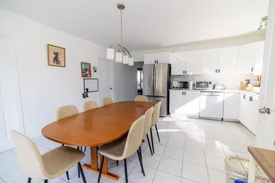 a kitchen and dining room with a wooden table and chairs at Spacious 4BDRS Entire House near DT, Free Parking in Longueuil