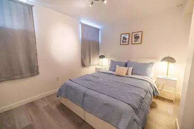 a bedroom with a bed and two lamps and a window at Spacious 4BDRS Entire House near DT, Free Parking in Longueuil