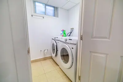 a white washer and dryer in a white laundry room at Spacious 4BDRS Entire House near DT, Free Parking in Longueuil