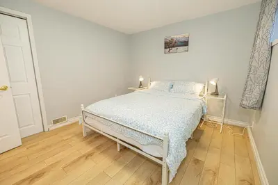 a white bedroom with a bed and a wooden floor at Entire NEW House 5BDR , close to DT MTL, 4 Parking in Brossard