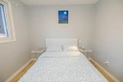 a bed in a white room with a picture on the wall at Entire NEW House 5BDR , close to DT MTL, 4 Parking in Brossard