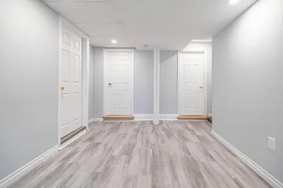 an empty room with white doors and wooden floors at Entire NEW House 5BDR , close to DT MTL, 4 Parking in Brossard