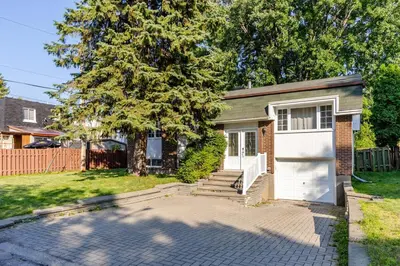a small brick house with a white garage at Quiet 4 BR House , 20 min to DT, Free Parking in Brossard