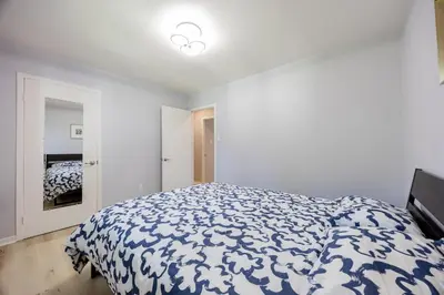 a bedroom with a bed with a blue and white comforter at Quiet 4 BR House , 20 min to DT, Free Parking in Brossard