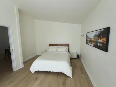 a bedroom with a white bed and a painting on the wall at Autumn Fairy Tale, Comfy Entire House with parking in Brossard