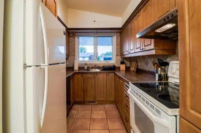 a kitchen with wooden cabinets and a white refrigerator at Autumn Fairy Tale, Comfy Entire House with parking in Brossard
