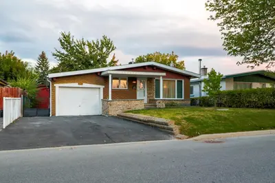 a red brick house with a white garage at Autumn Fairy Tale, Comfy Entire House with parking in Brossard