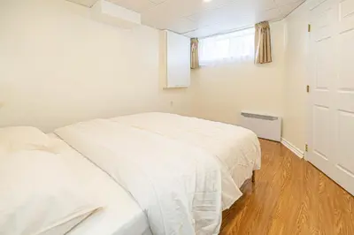 a white bedroom with two beds and a window at Spacious 2BDRs Apt,ALL NEW! Close to DT , 1 parking in Brossard