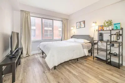 a bedroom with a bed and a desk and a television at Studio in heart of DT,walk to 2 metros,Concordia in Montréal
