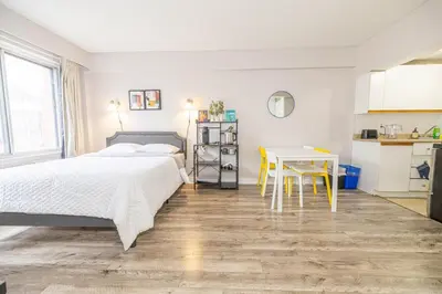 a bedroom with a bed and a table and a kitchen at Studio in heart of DT,walk to 2 metros,Concordia in Montréal