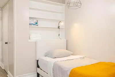 a white bedroom with a bed and a lamp at Studio in heart of DT,walk to 2 metros,Concordia in Montréal