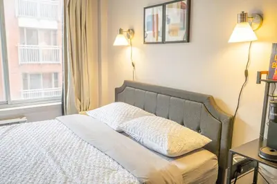 a bedroom with a bed with two lamps and a window at Studio in heart of DT,walk to 2 metros,Concordia in Montréal