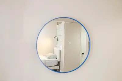 a round mirror on a white wall with a bedroom at Studio in heart of DT,walk to 2 metros,Concordia in Montréal
