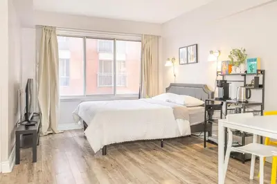 a bedroom with a bed and a desk and a television at Studio in heart of DT,walk to 2 metros,Concordia in Montréal